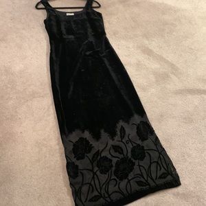 Long black velvet dress with sheer pattern at bottom.